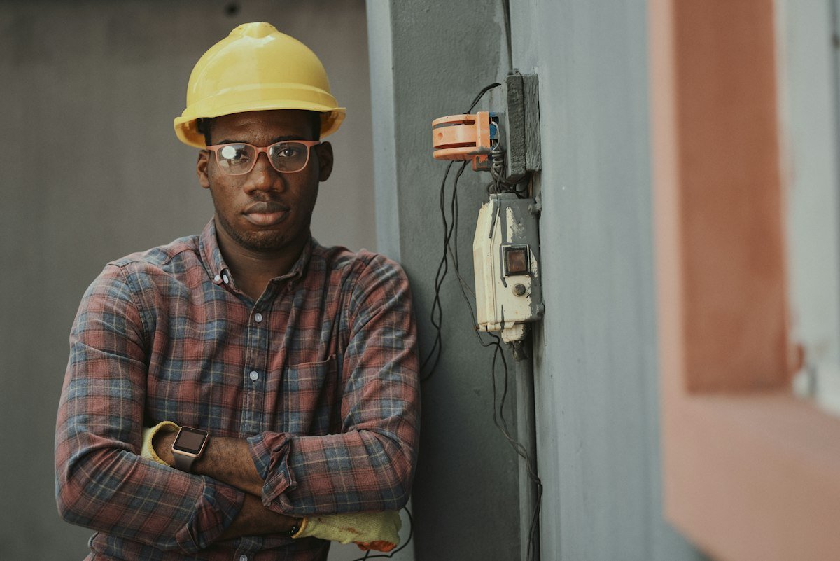 Licensed commercial electrician using testing instruments on heavy-duty three-phase industrial distribution switchboard