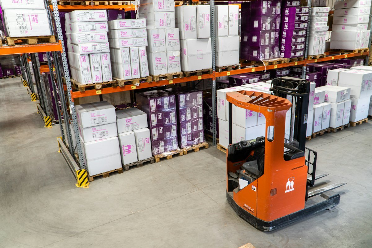 Commercial freight forwarding operations coordinator monitoring real-time fleet GPS tracking and warehouse inventory systems on multiple screens