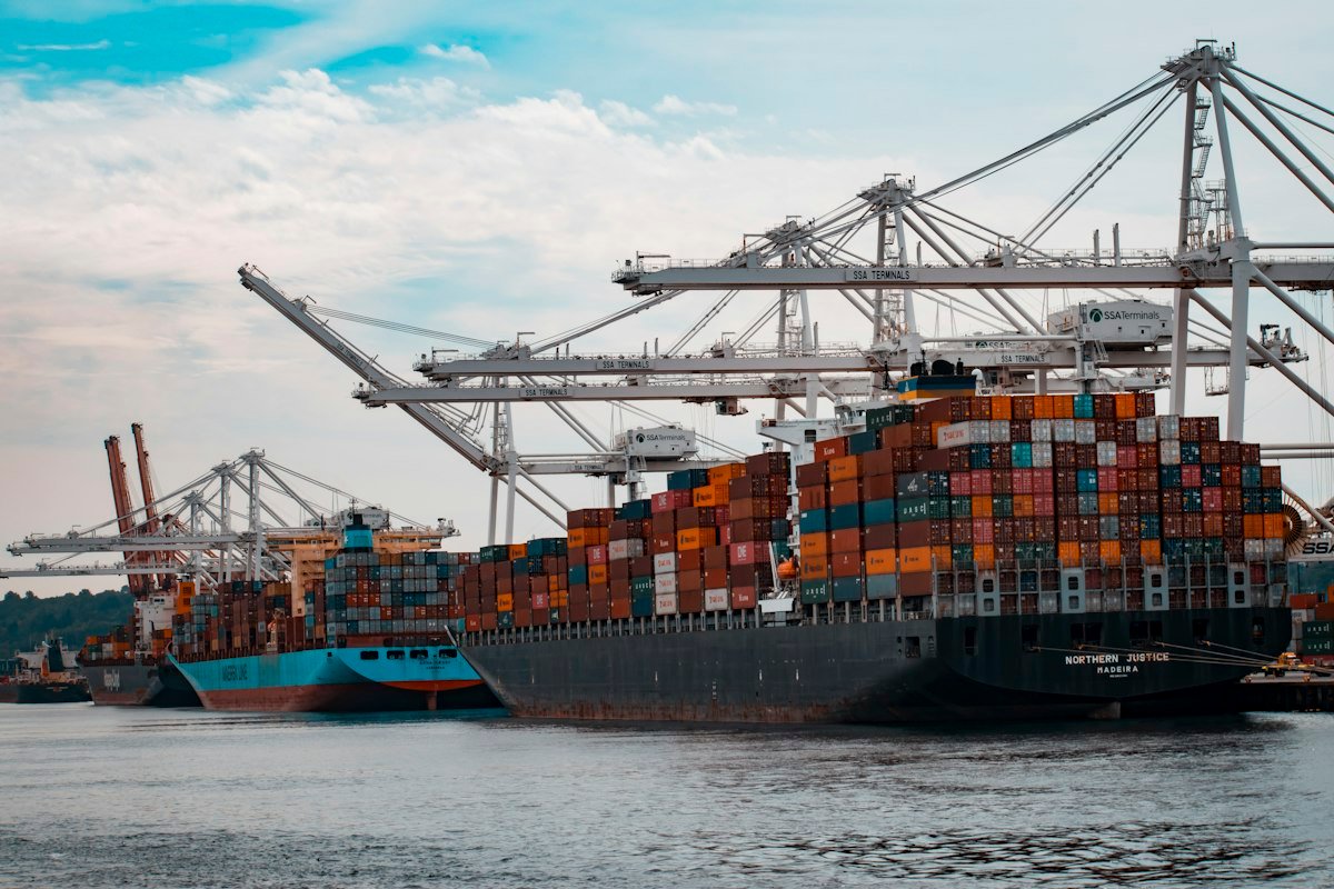 Intermodal freight forwarding terminal showcasing stacked shipping containers and commercial transport trucks ready for regional transit